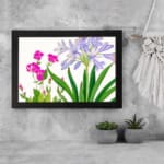Infidu Vintage Floral Wall Art with soft purple and bright pink flowers, green leaves, a white background, and a black frame for a stylish touch. displayed on the wall