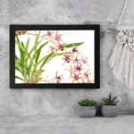 Infidu Vintage Orchid Floral Wall Art with white, pink, and purple orchids, yellow centers, and green leaves on a white background. displayed on the wall in a black frame