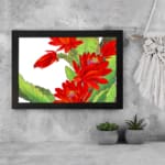 Vintage floral wall art with bold red flowers and green leaves on a white background, framed in black for a classic and stylish touch. displayed on the wall