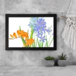 Vintage floral wall art with orange and blue flowers, green leaves, and a white background, framed in black for a classic and elegant look. displayed on the wall