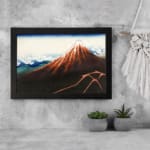 Vintage mountain landscape wall art with red, brown, and blue tones, featuring a striking reddish-brown mountain, blue sky, and black frame. displayed on the wall