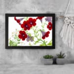 Vintage floral wall art with red and purple trumpet flowers, green leaves, and a black frame on a white background. displayed on the wall