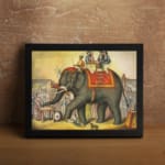 Vintage wall art of a grand elephant parade with red and gold decorations, surrounded by people in a festive village scene. displayed on the wall in a black frame