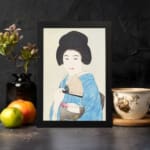 Vintage art of a Japanese woman in a light blue kimono holding a fan with a calm expression and soft background. displayed on the wall in a black frame