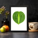 Heart-shaped green leaf with light and dark green patterns on a white background, framed in black, vintage botanical wall art displayed on the wall