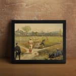 Vintage wall art of a classic baseball game with players in red and blue uniforms on a grassy field, trees and flags in the background. displayed on the wall in a black frame
