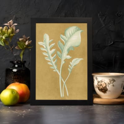 Vintage wall art of pale botanical fronds on an ochre background with a black frame. displayed on the wall in a black frame