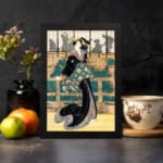 Vintage wall art of a Japanese woman in a black kimono with floral sash, standing before a traditional wooden building. displayed on the wall in a black frame