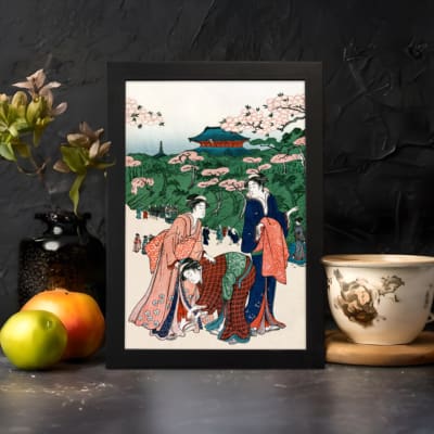 Vintage Japanese wall art of women in kimonos under cherry blossom trees with a temple in the background. displayed on the wall in a black frame