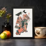 Two figures in traditional Japanese kimonos with orange, green, and black patterns standing gracefully on a plain white background. displayed on the wall in a black frame