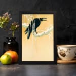 Infidu vintage wall art featuring a black crow perched on a snow-covered tree against a soft beige or light golden background, creating a timeless and artistic winter scene. displayed on the wall art in a black frame
