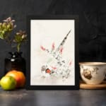 Vintage wall art with a bird surrounded by delicate flowers and plants in soft greens, reds, and whites, framed in black. displayed on the wall