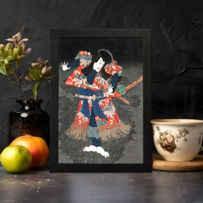 Japanese figure in bold red and blue kimono striking a dramatic pose against a dark vintage-style background. displayed on the wall in a black frame