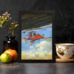 Infidu vintage wall art featuring a red airplane soaring through a bright blue sky with white clouds, evoking a sense of adventure and exploration. displayed on the wall art in a black frame