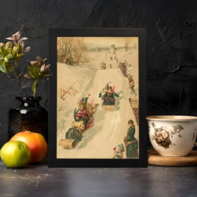 Vintage wall art of a nostalgic winter sledding scene with people in traditional winter clothing on a snowy slope, surrounded by trees. displayed on the wall in a black frame