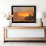 Vintage wall art of a tranquil sunset lake with warm tones, towering cliffs, and lush trees, creating a serene and timeless landscape. displayed on the wall in a black frame