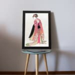 Vintage Japanese wall art of a woman in a floral kimono with intricate details, inspired by traditional woodblock prints, displayed on the table in a black frame