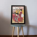 Vintage Japanese wall art with elegantly dressed women in kimonos, intricate patterns, and cherry blossom trees in a serene setting displayed on the table in a black frame