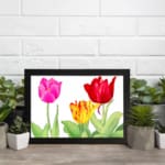 Infidu Vintage Floral Wall Art with pink, red, and yellow tulips, green leaves, and a black frame on a white background. displayed on the wall
