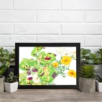 Vintage floral wall art with yellow flowers, green leaves, and a black frame on a white background. displayed on the wall