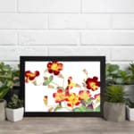 Vintage floral wall art with red, yellow, and orange flowers, green leaves, and a black frame on a white background. displayed on the wall