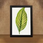 Vintage botanical wall art featuring a detailed green leaf with dark vein patterns on a white background, displayed on the wall in a black frame