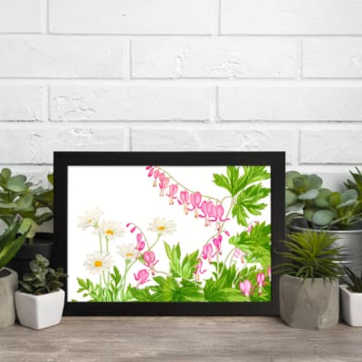 Vintage floral wall art with delicate pink and white flowers, green leaves, and a black frame on a white background. displayed on the wall