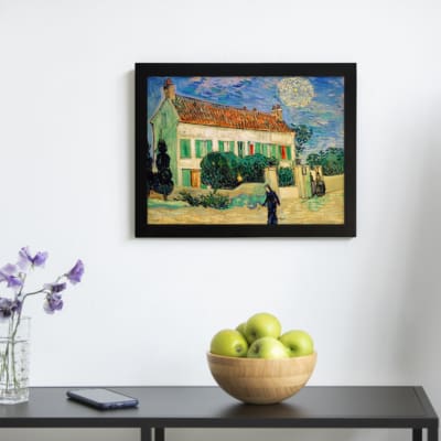 Infidu vintage wall art featuring a house with a red roof, green shutters, and a bright blue sky with the sun or moon shining, surrounded by lush grass and a walking path. displayed on the wall art in a black frame