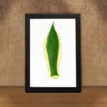 Minimalist green leaf design with yellow outline and dotted edges on white background, framed in black, vintage wall art. displayed on the wall in a black frame