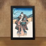 Vintage wall art of a Japanese samurai in a floral kimono standing in a peaceful winter scene with a snowy backdrop and a tree branch. displayed on the wall in a black frame