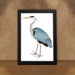 Vintage wall art of a graceful heron with blue and grey feathers on a white background, in a clean and minimalist style. displayed on the wall in a black frame