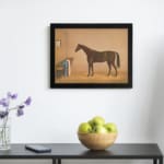 Infidu vintage wall art featuring an elegant horse standing in a cozy stable, with soft brown and beige tones, a small window, and rustic details. displayed on the wall art in a black frame