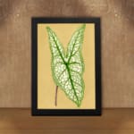 Vintage botanical wall art showing a detailed green leaf with bold veins on a soft beige background. displayed on the wall in a black frame