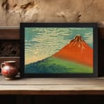 Infidu vintage wall art featuring an iconic view of Mount Fuji with a red-orange peak, a blue sky, and lush green surroundings in a traditional Japanese style. displayed on the wall art in a black frame