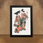 Two figures in traditional Japanese kimonos with orange, green, and black patterns standing gracefully on a plain white background. displayed on the wall in a black frame