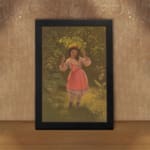 Infidu vintage wall art depicting a young girl in a pink dress holding a large green leaf over her head, set in a nostalgic outdoor scene with warm earthy tones. displayed on the wall art in a black frame
