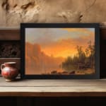 Vintage wall art of a tranquil sunset lake with warm tones, towering cliffs, and lush trees, creating a serene and timeless landscape. displayed on the wall in a black frame