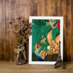 Vintage Asian-style mountain wall art with bold green hills, waterfalls, trees, and traditional red stamp. displayed on the wall in a white frame
