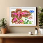 Vintage wall art featuring brown leaves with pink patterns and delicate blue, pink, and white flowers on a white background, framed in white. displayed on the wall