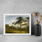 Vintage wall art of a serene forest with sunlight streaming through trees and distant hills in the background. displayed on the wall in a white frame