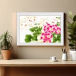Infidu vintage wall art with pink and white flowers, green leaves, and a white frame on a white background for a timeless and elegant look. displayed on the wall in a white frame