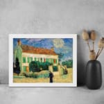 Infidu vintage wall art featuring a house with a red roof, green shutters, and a bright blue sky with the sun or moon shining, surrounded by lush grass and a walking path. displayed on the wall art in a white frame