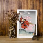 Infidu vintage wall art featuring a gracefully dressed figure in traditional Japanese attire against a serene moonlit sky, with rich red and pink floral designs contrasting a soft gray and blue background. displayed on the wall art in a white frame