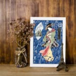 Japanese woman in colorful kimono with calligraphy background, vintage art style displayed on the wall in a white frame
