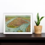 Vintage aerial view of a historic waterfront city with detailed buildings, boats, and earthy tones. displayed on the wall in a white frame