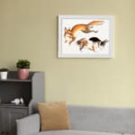 Vintage wall art of a fox and two rabbits in motion, hand-drawn in natural colors with a clean white background. displayed on the wall in a white frame