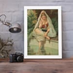 Vintage wall art of a woman sitting by a peaceful pool, surrounded by tropical plants, wearing traditional attire with a headscarf and jewelry. displayed on the wall