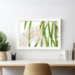 Vintage floral wall art with white orchids and green leaves, framed in white for a classic and elegant look. displayed on the wall