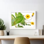 Vintage floral wall art with bright yellow flowers, green leaves, and a white frame on a white background. displayed on the wall
