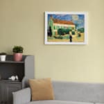 Infidu vintage wall art featuring a house with a red roof, green shutters, and a bright blue sky with the sun or moon shining, surrounded by lush grass and a walking path. displayed on the wall art in a white frame